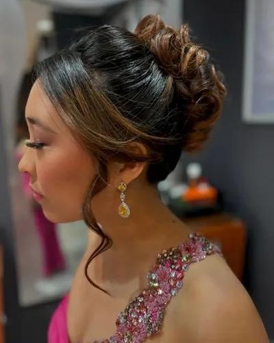 A high curled bun with soft face-framing tendrils, styled for a formal event